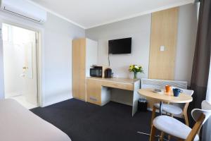 a hotel room with a desk and a table at Nebula Motel in Cooma