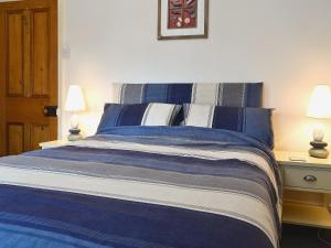 a bed with blue and white sheets and two lamps at Castle Street in Llanystumdwy