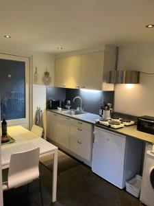 cocina con armarios blancos, mesa y fregadero en Jaguars Residence en Eindhoven