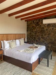 1 dormitorio con cama y pared de piedra en Siempre Valle Hotel Boutique, en Valle de Guadalupe