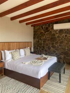 um quarto com uma cama e uma parede de pedra em Siempre Valle Hotel Boutique em Valle de Guadalupe