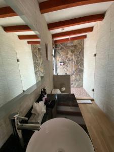 a bathroom with a toilet and a stone wall at Siempre Valle Hotel Boutique in Valle de Guadalupe