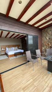 eine Terrasse mit einem Bett, 2 Stühlen und einem Tisch in der Unterkunft Siempre Valle Hotel Boutique in Valle de Guadalupe