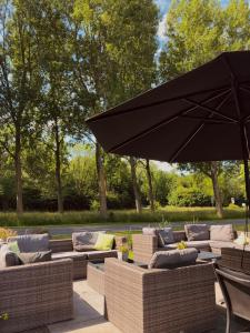 a patio with couches and a large black umbrella at Hotel Molengroet in Noord-Scharwoude