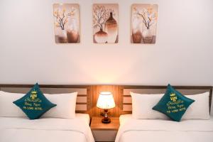 two beds in a room with pictures on the wall at Hồng Ngọc Hạ Long Hotel in Ha Long