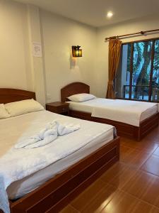 2 Betten in einem Zimmer mit Handtüchern darauf in der Unterkunft Bank Guesthouse in Haad Rin