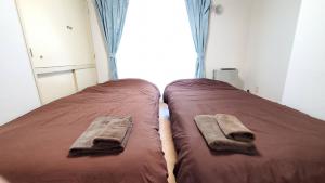 twee bedden in een slaapkamer met twee handdoeken erop bij 直前半額プライベート個室トイレバスタブ付民泊札幌市中心部でシンプルな滞在h503#12 in Sapporo