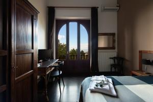 a bedroom with a bed and a desk and a window at Domus Verdiana in Ragalna