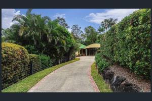 una entrada que conduce a una casa con árboles y arbustos en Noosa hinterland acreage close to the beach, en Ninderry