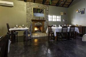 a dining room with tables and chairs and a fireplace at Royal Bakoena Hamiltonparks Country Lodge in Hazyview