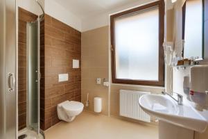 baño con lavabo y aseo y ventana en Lopušná dolina Resort, en Vysoké Tatry