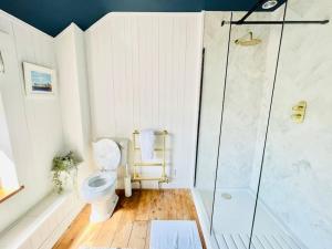 La salle de bains blanche est pourvue d'une douche et de toilettes. dans l'établissement * Fisherman’s Cottage * with river views (dog friendly!), à Appledore