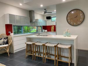 a kitchen with a large clock on the wall and stools at The Palm - Beachside Home with Heated Pool & Cinema in Mudjimba
