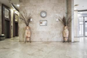 een lobby met twee vazen aan de muur met een klok bij ISRALUX APARTMENTS in Bat Yam