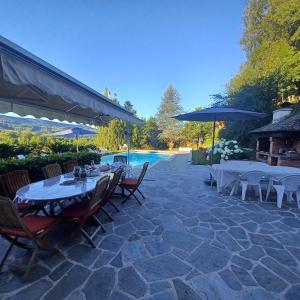 un patio con mesas y sillas y una piscina en La Grange de Lily en Vic-sur-Cère