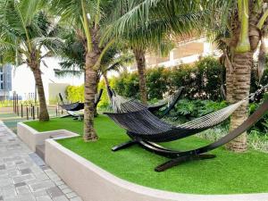 two hammocks in a resort yard with palm trees at Bali Residence I B3105 Luxury 2BR I Seaview I 6-9pax l WaterPark I CityCentre by Jay Stay in Melaka