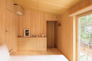 輕井澤的住宿－SHISHI-IWA-HOUSE Karuizawa，一间设有木墙和一张带窗户的床的客房
