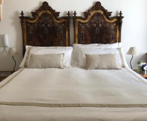 een groot wit bed met een houten hoofdeinde en kussens bij Antica Casa del Pozzo in Manduria