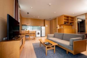 a living room with a couch and a tv at Sanae' Hotel Nimman in Chiang Mai