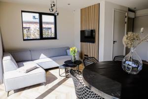 een woonkamer met een bank en een tafel bij Prachtige bungalow op vakantiepark bij zee. in Baarland