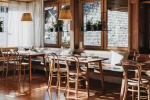 Hotel Post Bezau في بيزاو: مطعم بطاولات وكراسي خشبية ونوافذ