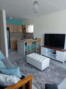 a living room with a couch and a tv and a kitchen at Phoenix, Langenhovenpark, Bfn near Inibos parkrun. in Bloemfontein