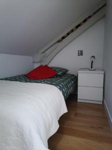a bedroom with a white bed with a red pillow at Gîte LA Maison LA in Saint-Aubin-dʼAubigné