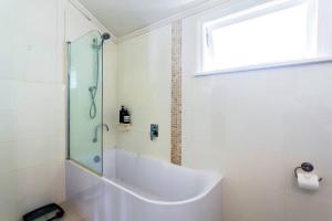 een badkamer met een bad en een glazen douche bij Garden Cottage 1Brm Private & Spacious in Brisbane