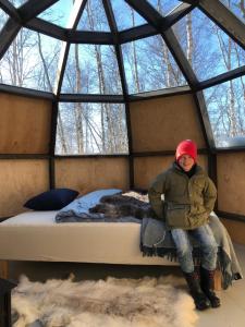 a person sitting on a bed in a room with windows at Environmental friendly Ecolodge in Haugen