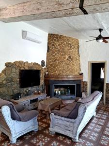 sala de estar con chimenea de piedra y TV en Hacienda Tresoles en Ubrique