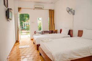 a bedroom with two beds and a window and a table at Thiên Tân Hotel in Con Dao