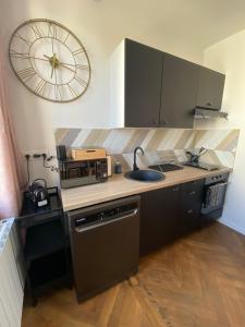 a kitchen with a sink and a clock on the wall at Pink Cosy in Louviers