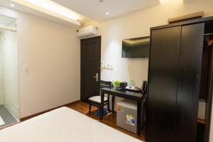 a small room with a desk and a black refrigerator at Queen Central Hotel - Ben Thanh Market in Ho Chi Minh City