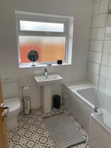 a bathroom with a sink and a toilet and a window at Plum Tree Corner in Chapel Saint Leonards +21 photos