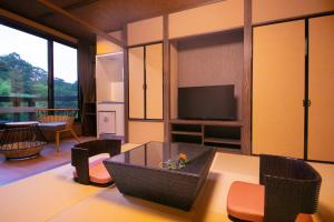 a living room with a table and a television at Hosenji Kanko Hotel Yumotoya in Kokonoe