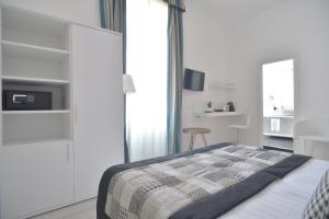 a white bedroom with a bed and a chair at Lata Luxury Rooms in Rome