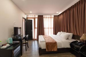 ein Hotelzimmer mit einem Bett, einem Schreibtisch und einem TV in der Unterkunft Queen Central Hotel - Ben Thanh Market in Ho-Chi-Minh-Stadt
