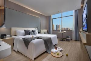 a bedroom with a large white bed and a large window at Spey Hotel in Guangzhou
