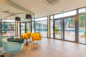 Appart'City Confort Toulouse Purpan في تولوز: غرفة معيشة مع كراسي صفراء وأبواب زجاجية منزلقة