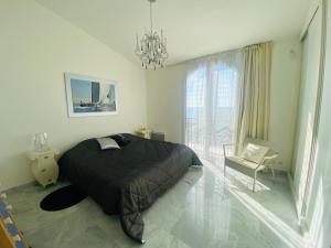 1 dormitorio con 1 cama, 1 silla y 1 lámpara de araña en Appartement de la mer, en Sainte-Maxime