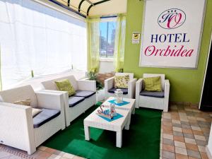 hol hotelowy z kanapami, stołami i znakiem w obiekcie Hotel Orchidea w Lignano Sabbiadoro