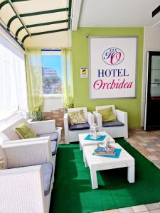 リニャーノ・サッビアドーロにあるHotel Orchideaの白い家具と緑の敷物が備わるホテルオフィス