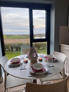 une table blanche avec des assiettes et des verres ainsi qu'une fenêtre dans l'établissement The Boathouse, à Donaghadee