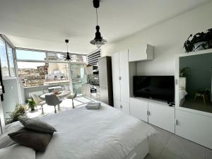 um quarto branco com uma cama grande e uma televisão em Cosy Penthouse in Hamrun - Walking distance to Valletta em Hamrun
