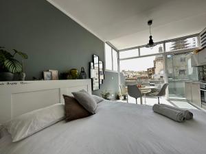um quarto com uma cama branca e uma grande janela em Cosy Penthouse in Hamrun - Walking distance to Valletta em Hamrun
