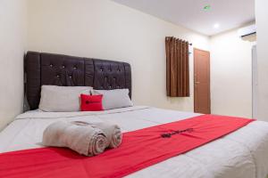 um quarto com uma cama grande e um cobertor vermelho em RedDoorz @ Medan Johor 2 em Delitua