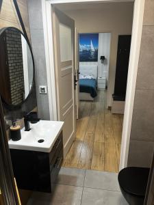 a bathroom with a sink and a mirror and a bed at Apartamenty Na Fali in Darłówko