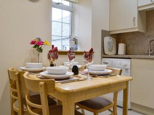a kitchen with a wooden table with plates and wine glasses at Mill Shore Cottage - 26817 in Pennan