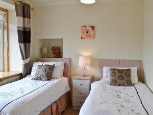 two beds sitting next to each other in a bedroom at Mill Shore Cottage - 26817 in Pennan