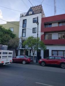 阿瓜斯卡連特斯的住宿－Chulada de Departamento，两辆汽车停在大楼前